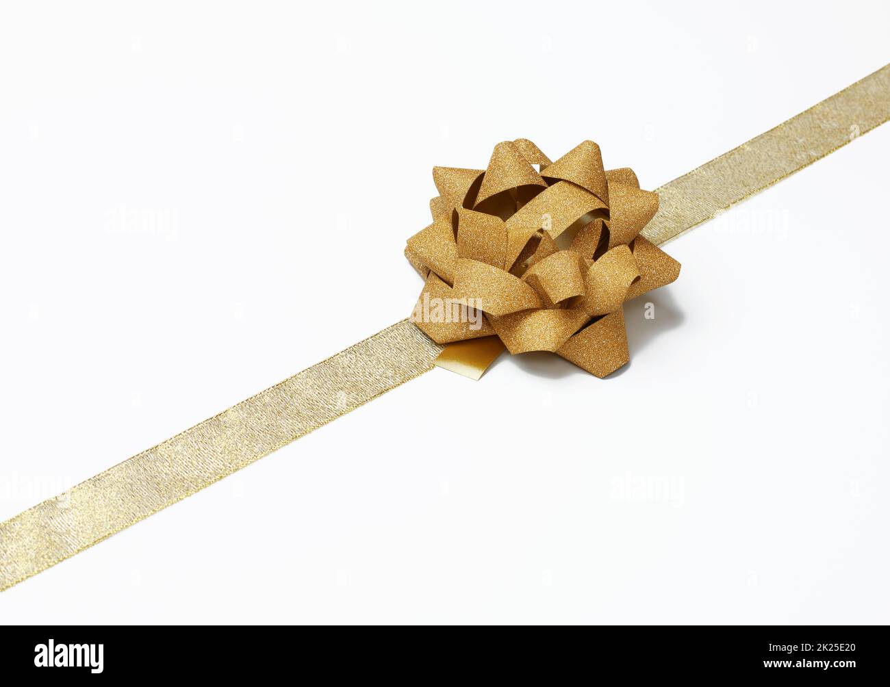 lazo y cinta de seda dorada sobre fondo blanco, elemento de diseño para decoración de regalo Foto de stock