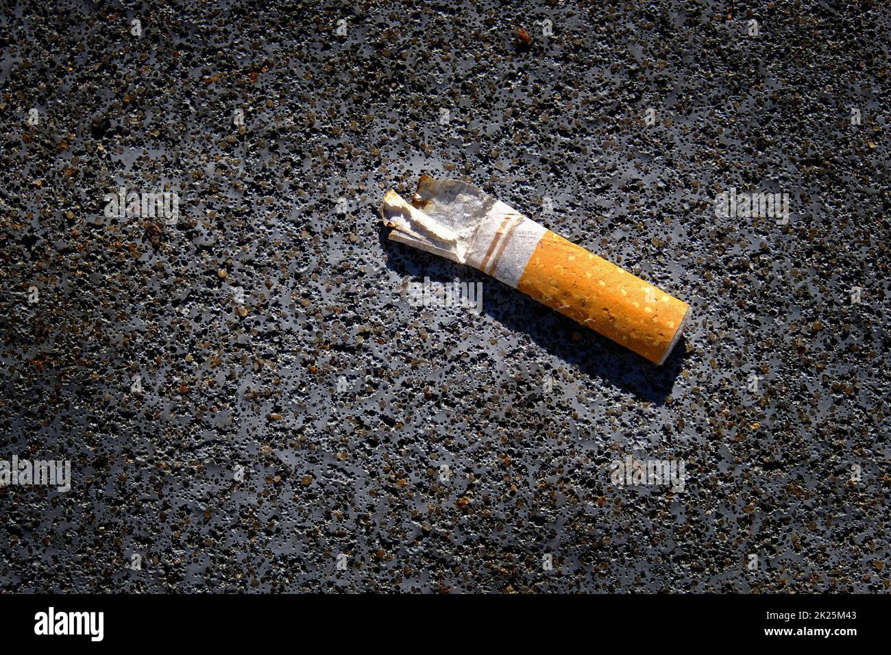 Cigarrillo abandonado colilla en concreto texturizado y sucio mal hábito Foto de stock