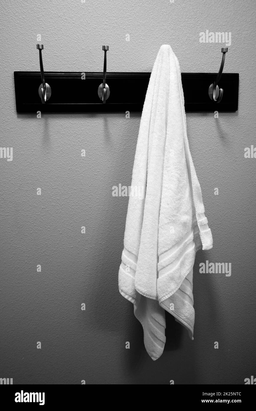 Toalla blanca individual en colginbg de rejilla en la pared del baño Foto de stock