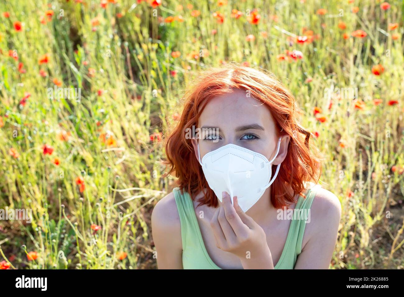 niña frustrada con máscara protectora en el campo de amapola Foto de stock