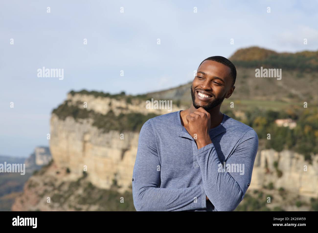 Hombre feliz con piel negra pensando en la montaña Foto de stock