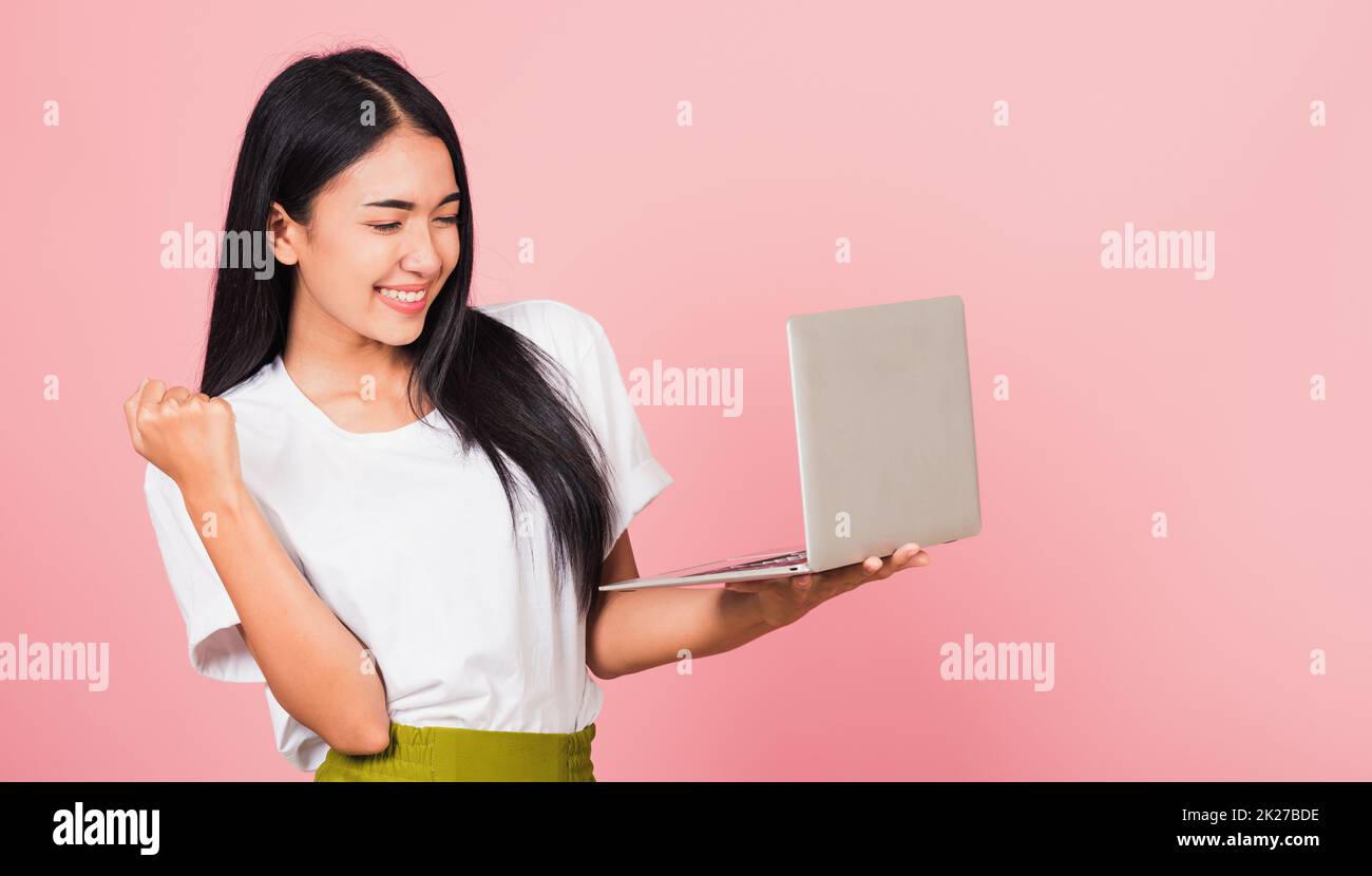 mujer adolescente confidente sonriente cara que sostiene usando computadora portátil y celebración excitado Foto de stock
