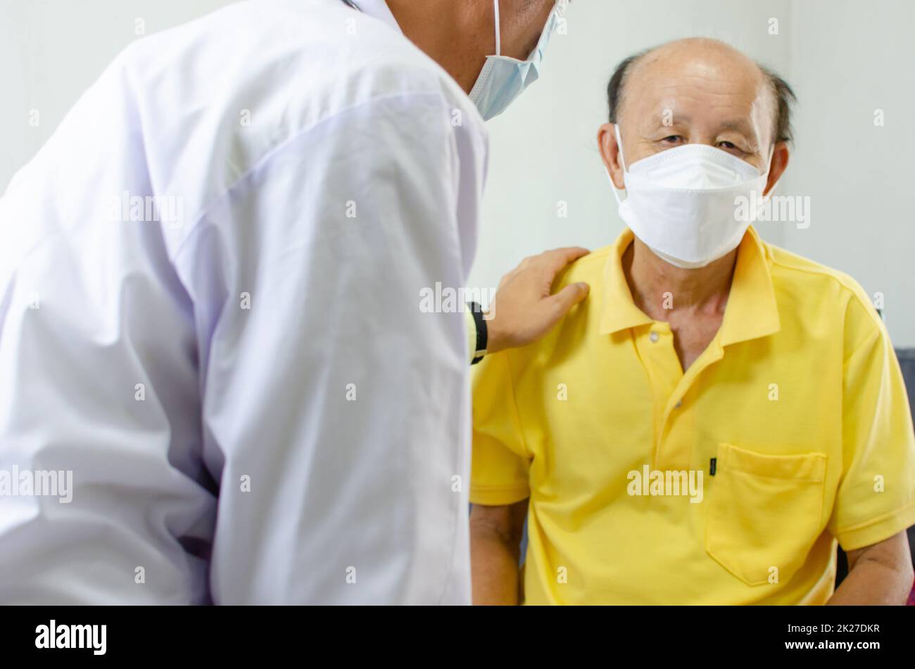 el doctor sujetó su hombro y habló con un hombre mayor que estaba enfermo para darle aliento. Foto de stock