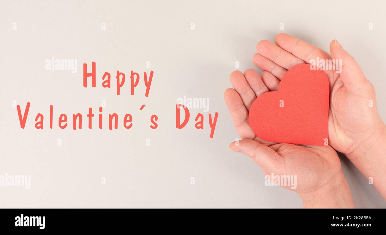 Sosteniendo un corazón en las manos, celebrando el día de San Valentín en febrero, símbolo de amor Foto de stock
