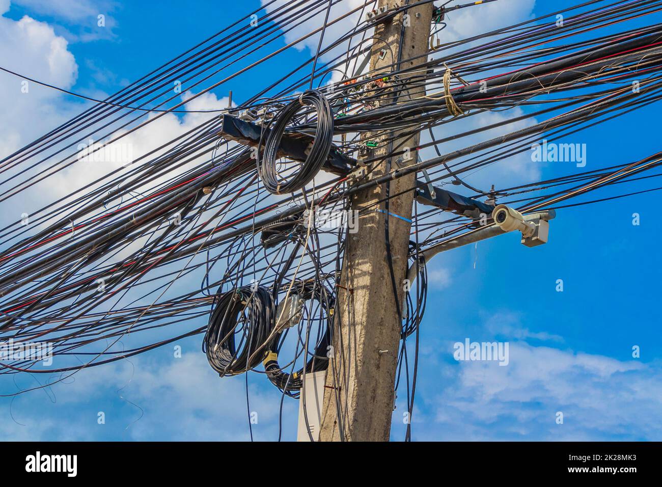 Caos absoluto del cable en el polo de energía tailandés cielo azul de Tailandia. Foto de stock