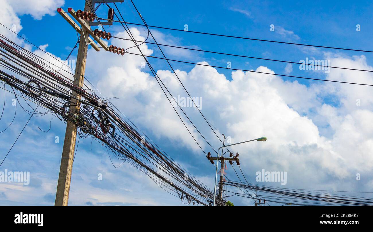 Caos absoluto del cable en el polo de energía tailandés cielo azul de Tailandia. Foto de stock