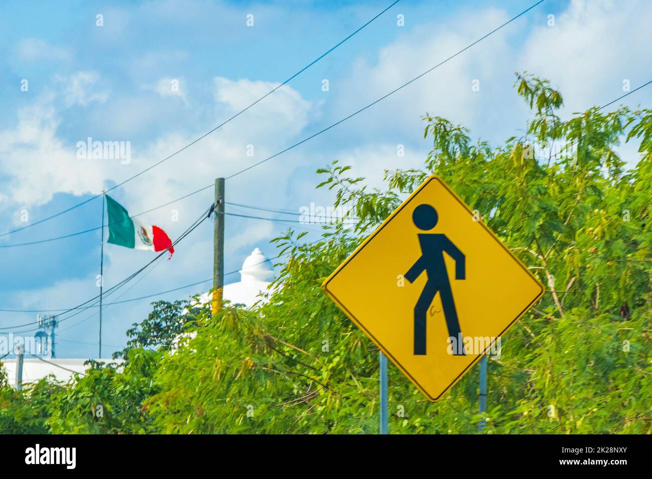 Señal amarilla de la carretera peatonal en la ciudad de Playa del Carmen Quintana Roo México con bandera mexicana. Foto de stock