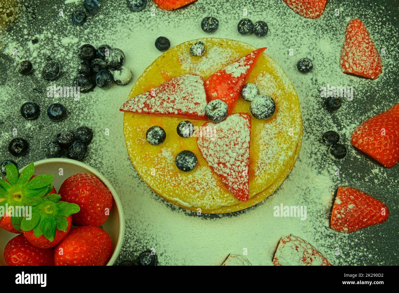 Saludable desayuno de verano, tortitas americanas clásicas caseras con bayas frescas y azúcar glasé. Arándanos y fresas en panqueques. Fondo negro, plano Foto de stock