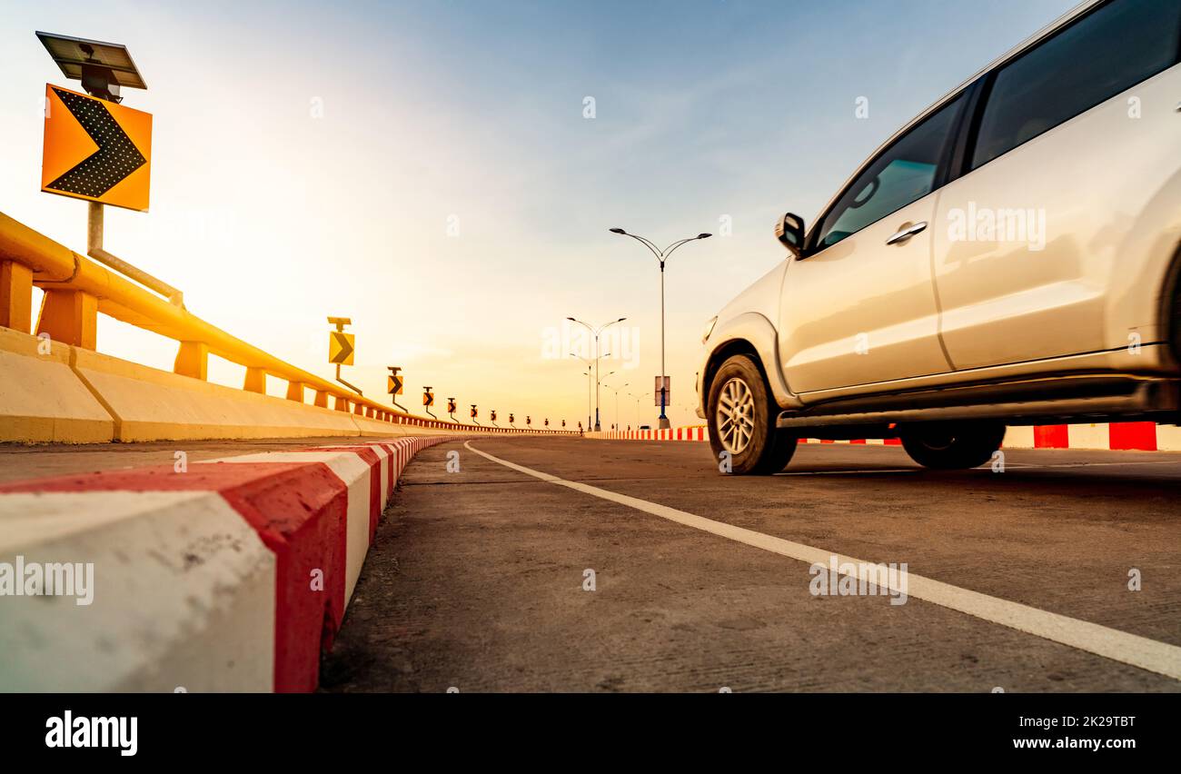 Carretera de hormigón en curva con señal de tráfico en curva y señal de stop rojo-blanco prohibido. Panel solar de energía en curva señal de tráfico. Viaje por carretera. Desenfoque por movimiento de un coche blanco circulando por la carretera. Viaje por carretera en verano. Foto de stock