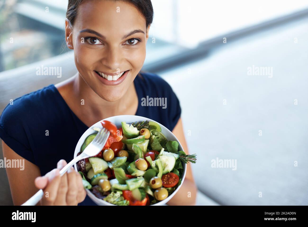 Comer una dieta equilibrada es tan importante. Vista superior de una hermosa mujer joven disfrutando de una saludable ensalada en su casa. Foto de stock