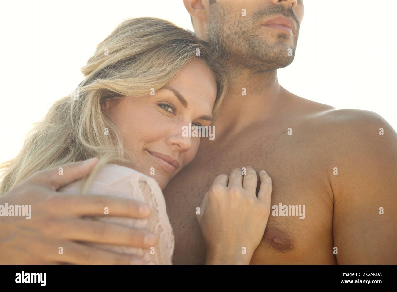 Seguro en sus brazos. Retrato de cabeza y hombros de una joven atractiva abrazando a su marido en un día soleado. Foto de stock