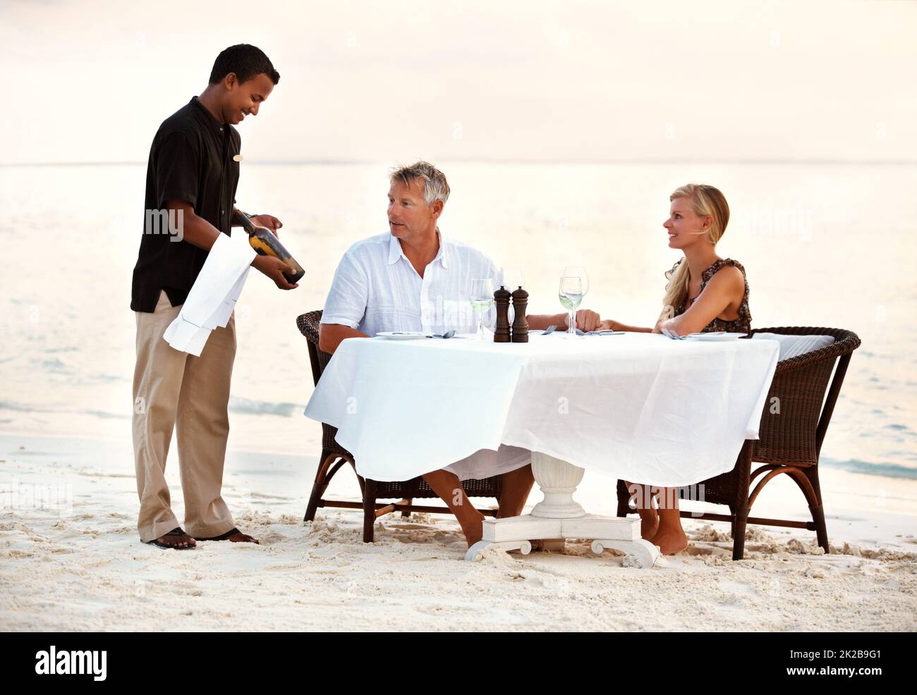 Pareja adulta cenando en la playa. Foto de una pareja adulta disfrutando de una cena romántica en la playa. Foto de stock