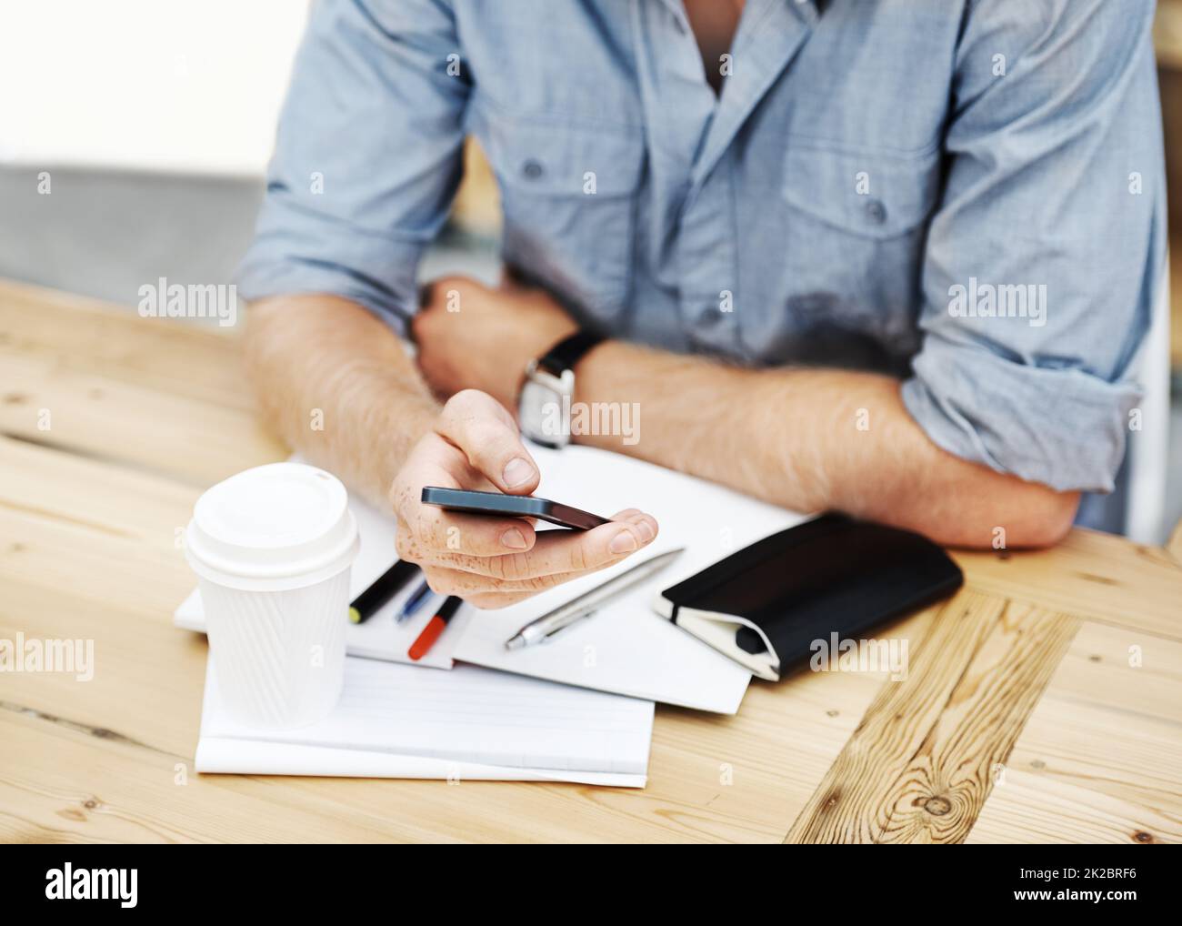 Comunicación empresarial. Foto recortada de un diseñador utilizando su smartphone mientras estaba sentado en la oficina. Foto de stock