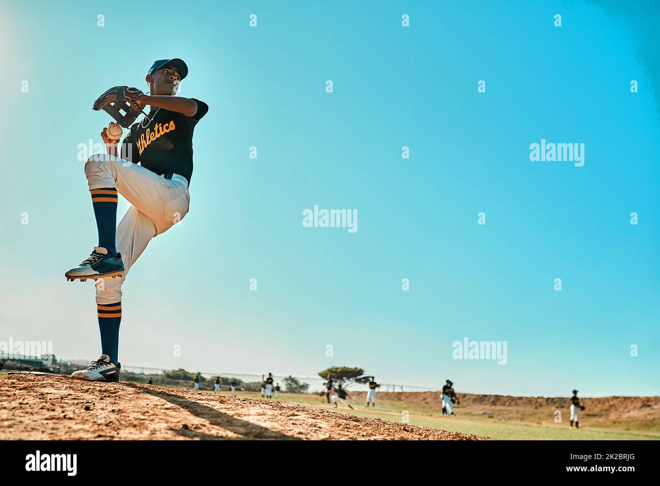 Prepárese. Tiro de un joven jugador de béisbol lanzando la pelota durante un juego al aire libre. Foto de stock