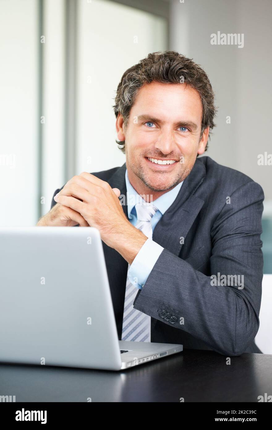 Sonriente hombre de negocios con portátil. Retrato de un hombre de negocios con un portátil y una cálida sonrisa. Foto de stock