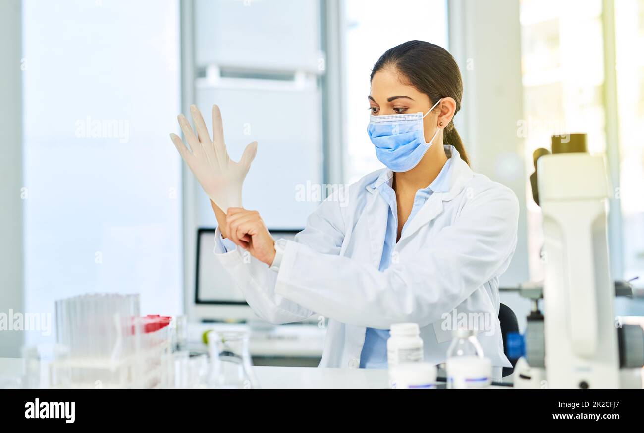 Listo para profundizar en alguna investigación científica. Foto de un joven científico que se puso guantes protectores en un laboratorio. Foto de stock