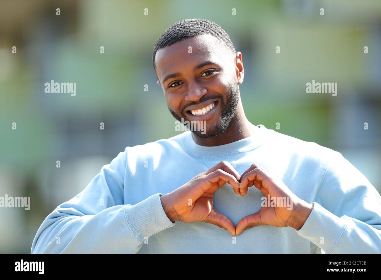 Hombre feliz con piel negra haciendo forma de corazón Foto de stock