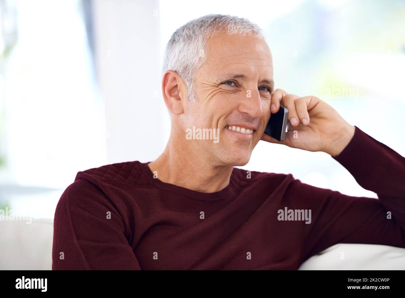 La felicidad es escuchar su voz. Un hombre maduro que tiene una divertida conversación telefónica. Foto de stock