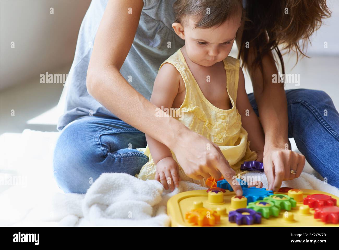 Aprender con mamá. Tiro de una linda niña sentada en el suelo con su ...