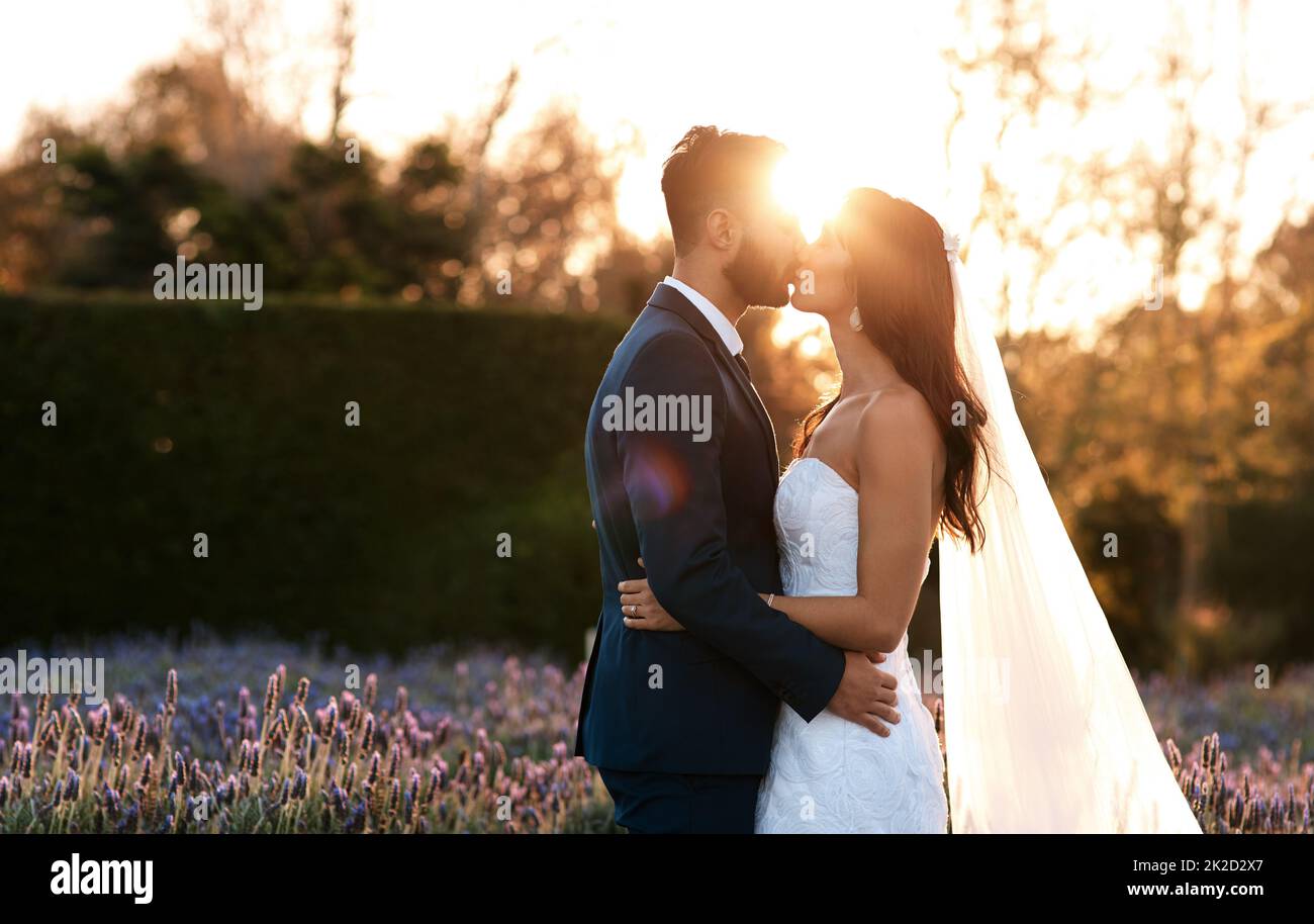 Nuestro amor sólo seguirá creciendo. Disparo recortado de una pareja joven besando en su día de boda. Foto de stock