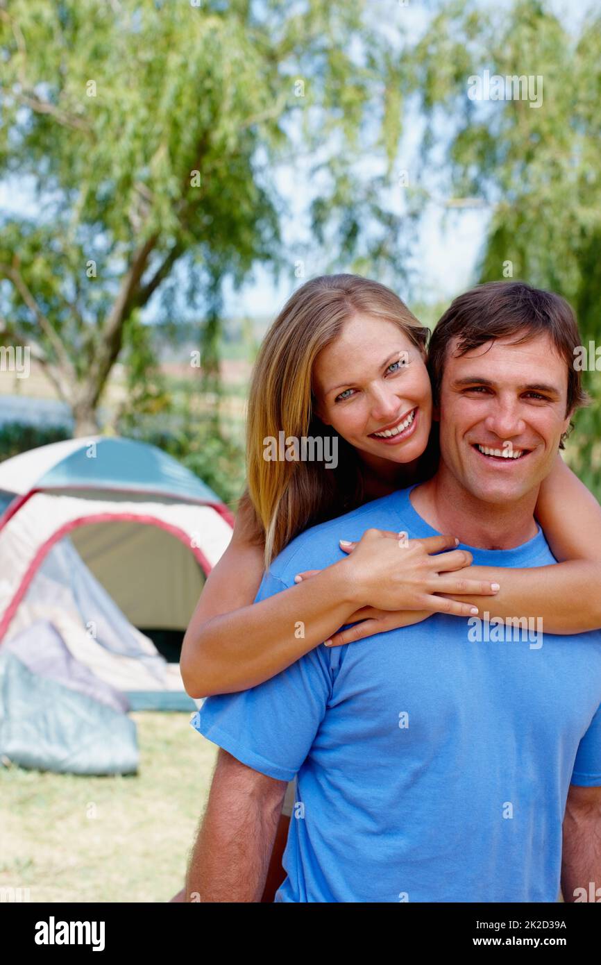 Pareja amorosa. Retrato de pareja acampando con mujer abrazando al hombre desde atrás. Foto de stock