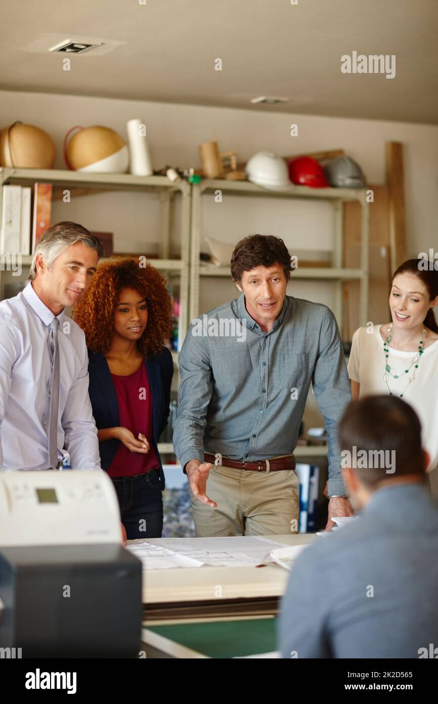 Deberíamos golpear mientras los hierros calientes. Foto de un grupo de arquitectos que tienen una reunión en su oficina. Foto de stock