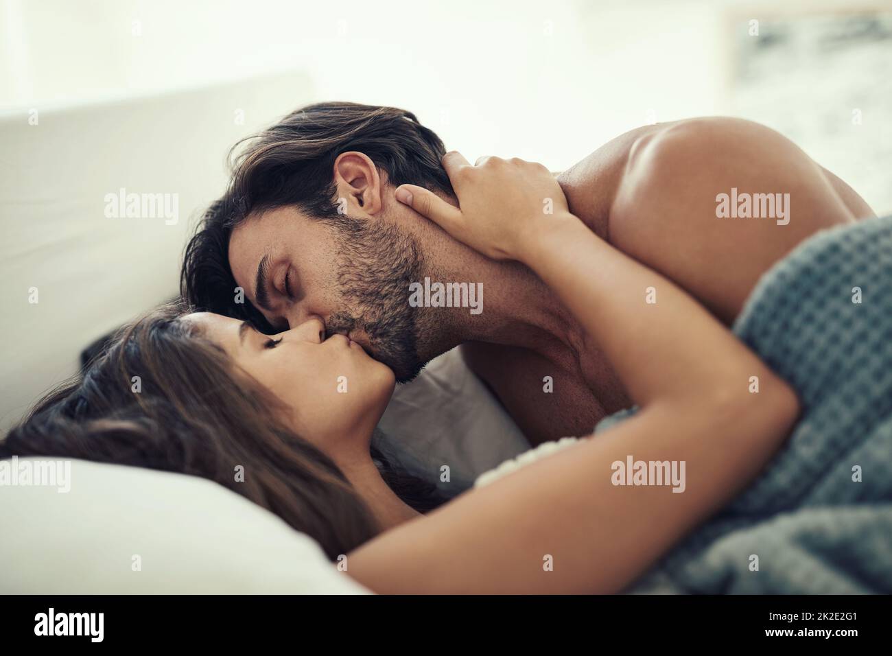 Ser íntimo. Foto recortada de una pareja joven cariñosa siendo íntima en la cama. Foto de stock