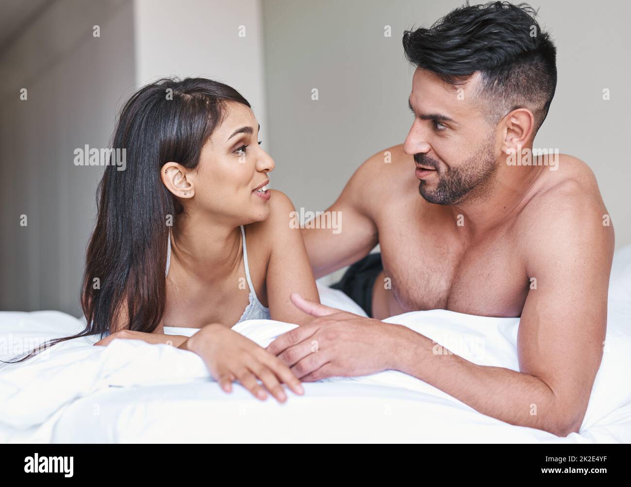 Hoy utilizamos la conversación para despertar. Foto recortada de una joven pareja casada cariñosa en la cama en casa. Foto de stock