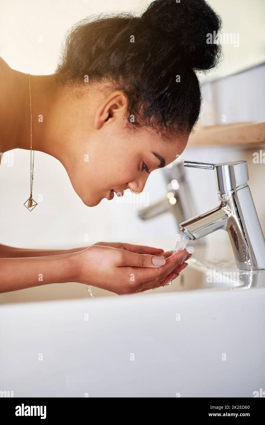 La piel sana es un compromiso diario. Disparo de una mujer joven lavando su cara en el lavabo del baño. Foto de stock