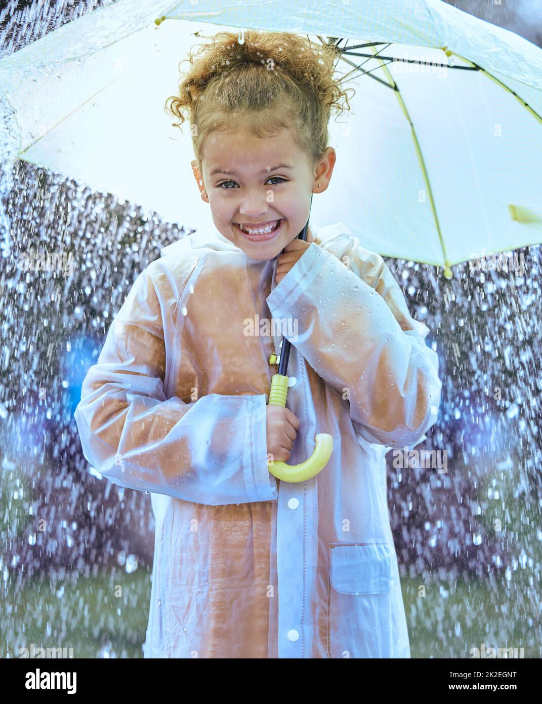 Esto es muy emocionante. Foto de una niña juguetonamente de pie en la lluvia sosteniendo su paraguas. Foto de stock