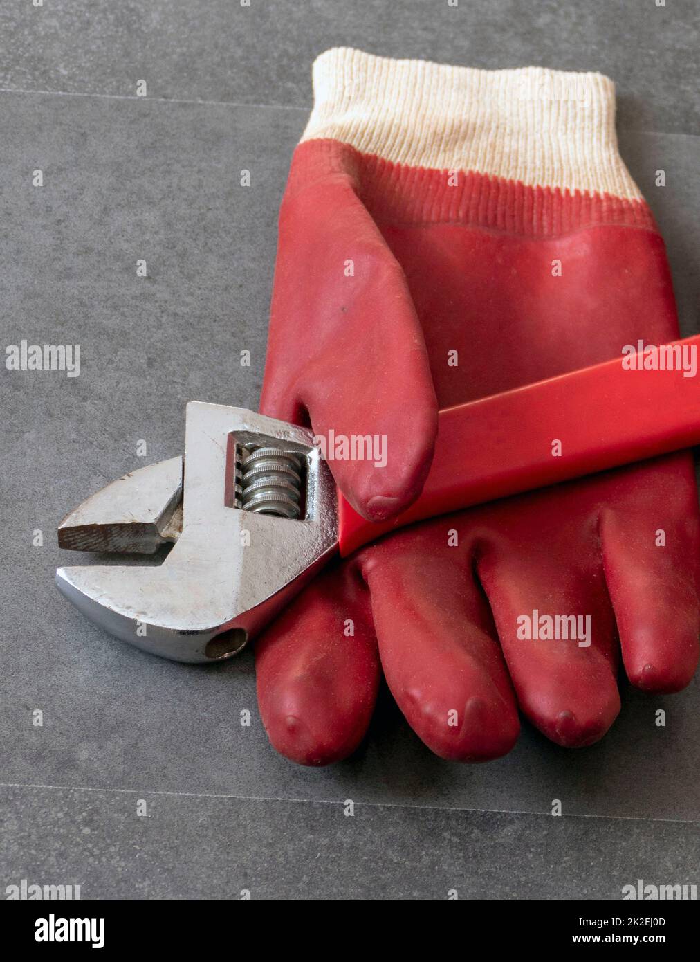 Por motivos de seguridad en el trabajo, es necesario trabajar con guantes, una llave, guantes gruesos de plástico sobre el suelo Foto de stock