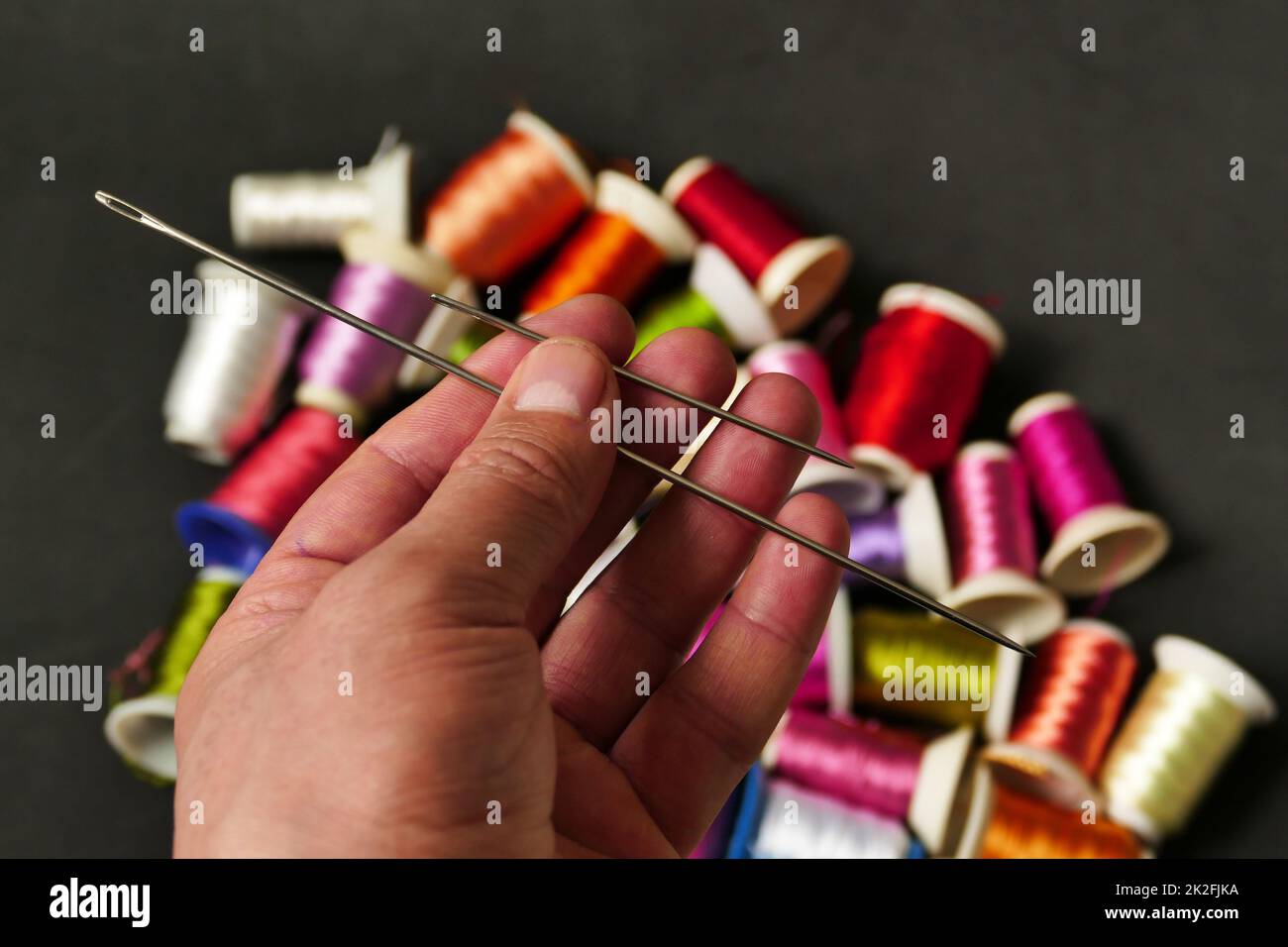 aguja de coser clásica y los hilos en la mano de un sastre, aguja de coser primer plano Foto de stock
