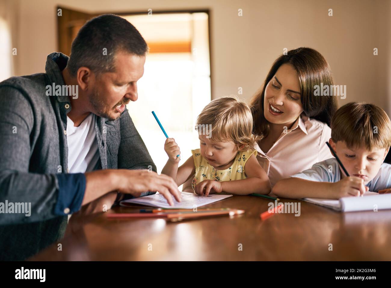 Involucrando a sus hijos en el juego creativo. Foto de una familia joven de cuatro dibujos y conseguir creativos juntos en casa. Foto de stock