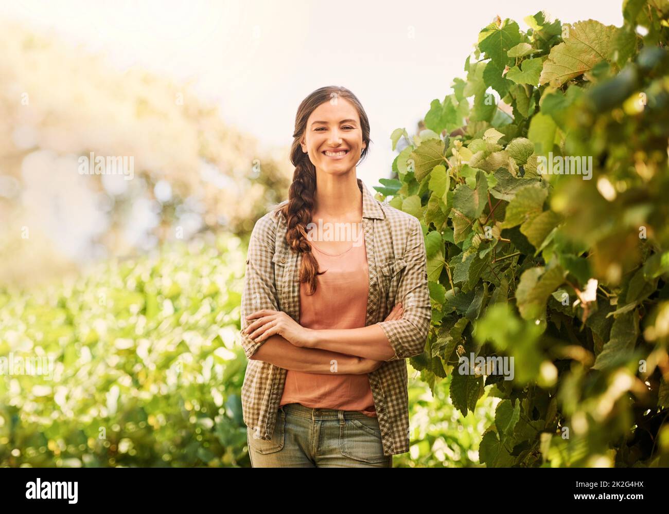 Retrato de una joven y alegre campesina posando en los campos de su granja. Foto de stock
