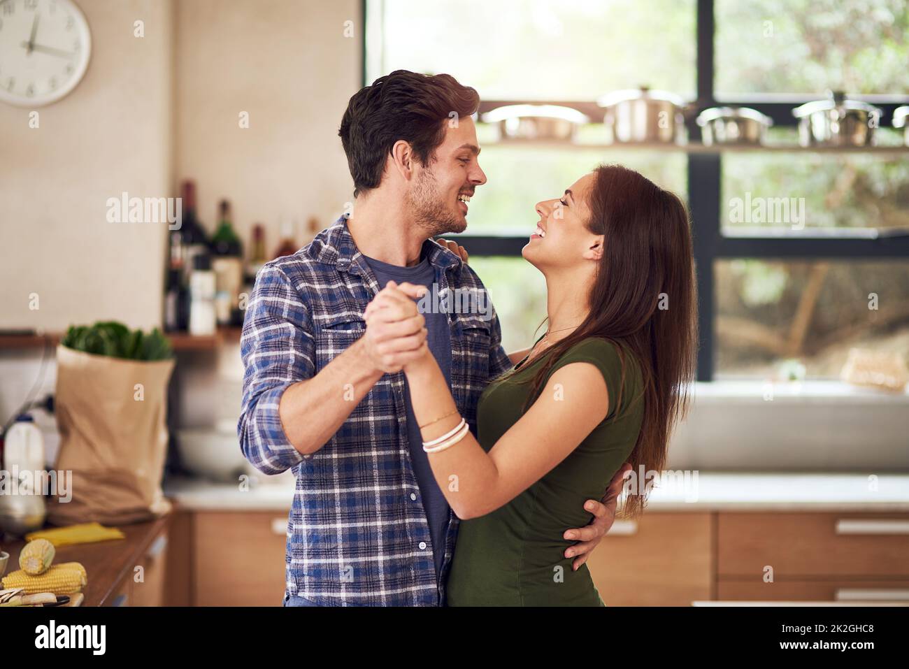 El amor nos hace aligerados. Foto de una feliz pareja joven bailando en su cocina en casa. Foto de stock