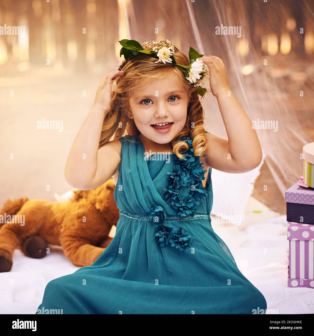 Las flores son importantes para una princesa de hadas. Foto de una niña feliz mirando la cámara y tocando una corona de flores en su cabeza mientras estaba sentada fuera en el bosque. Foto de stock