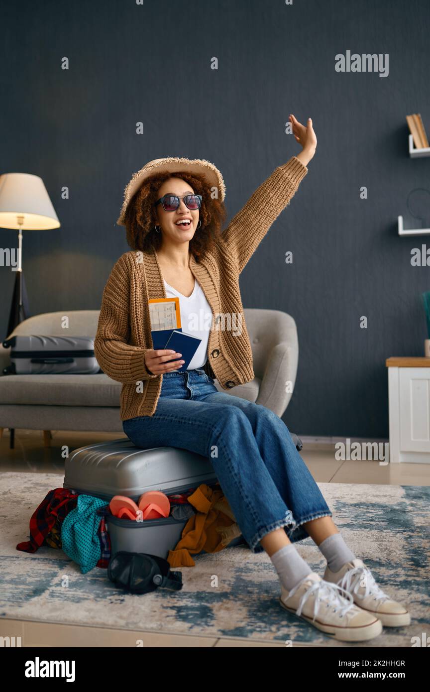 Mujer sentada en la maleta con ropa en exceso Foto de stock