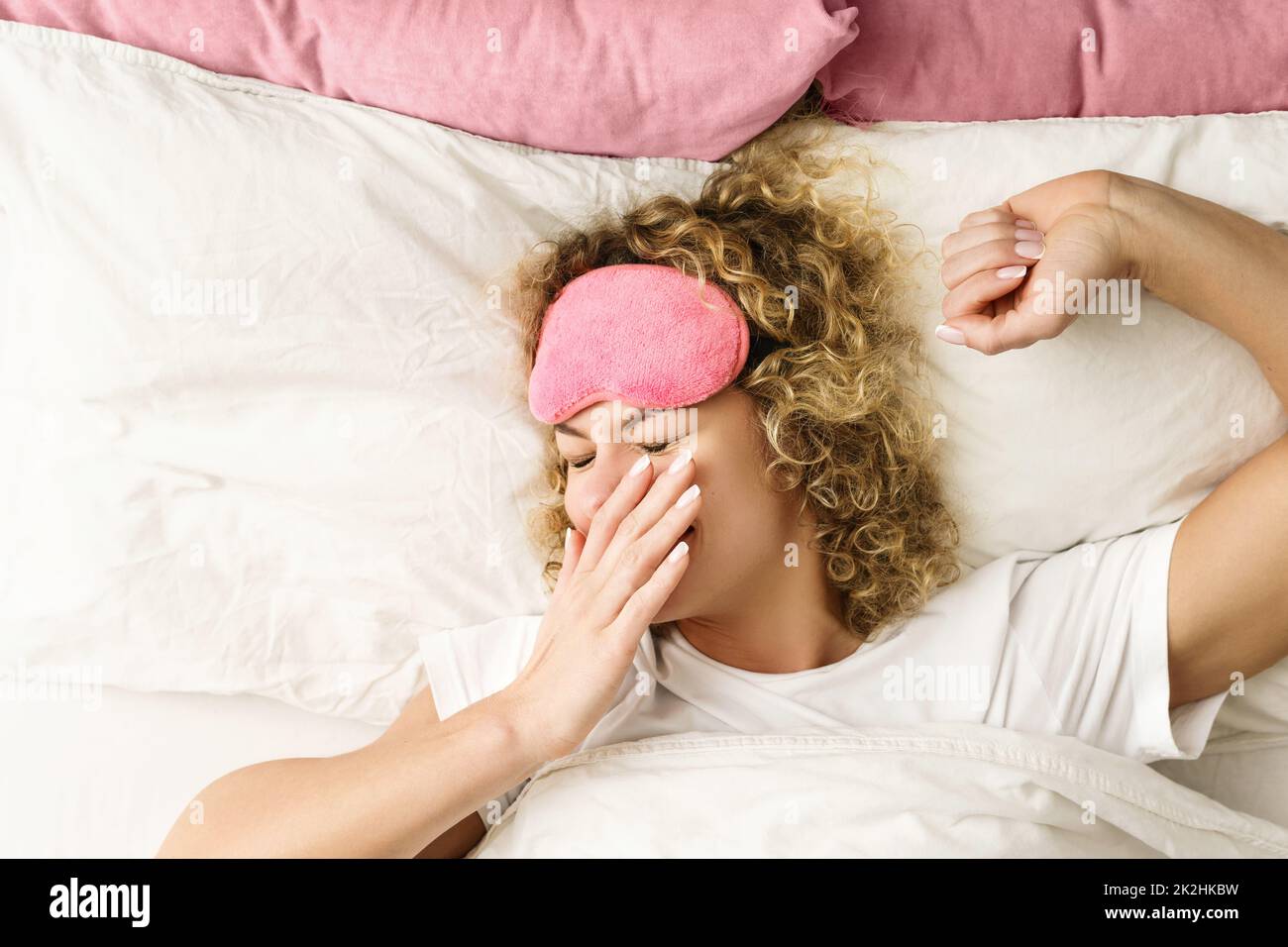 Mujer hermosa con el pelo rizado despertando después de un buen sueño Foto de stock