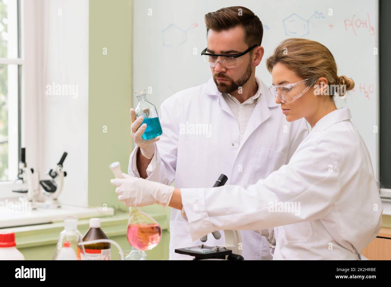 Científicos colegas están trabajando con reactivos químicos en un laboratorio durante la investigación Foto de stock