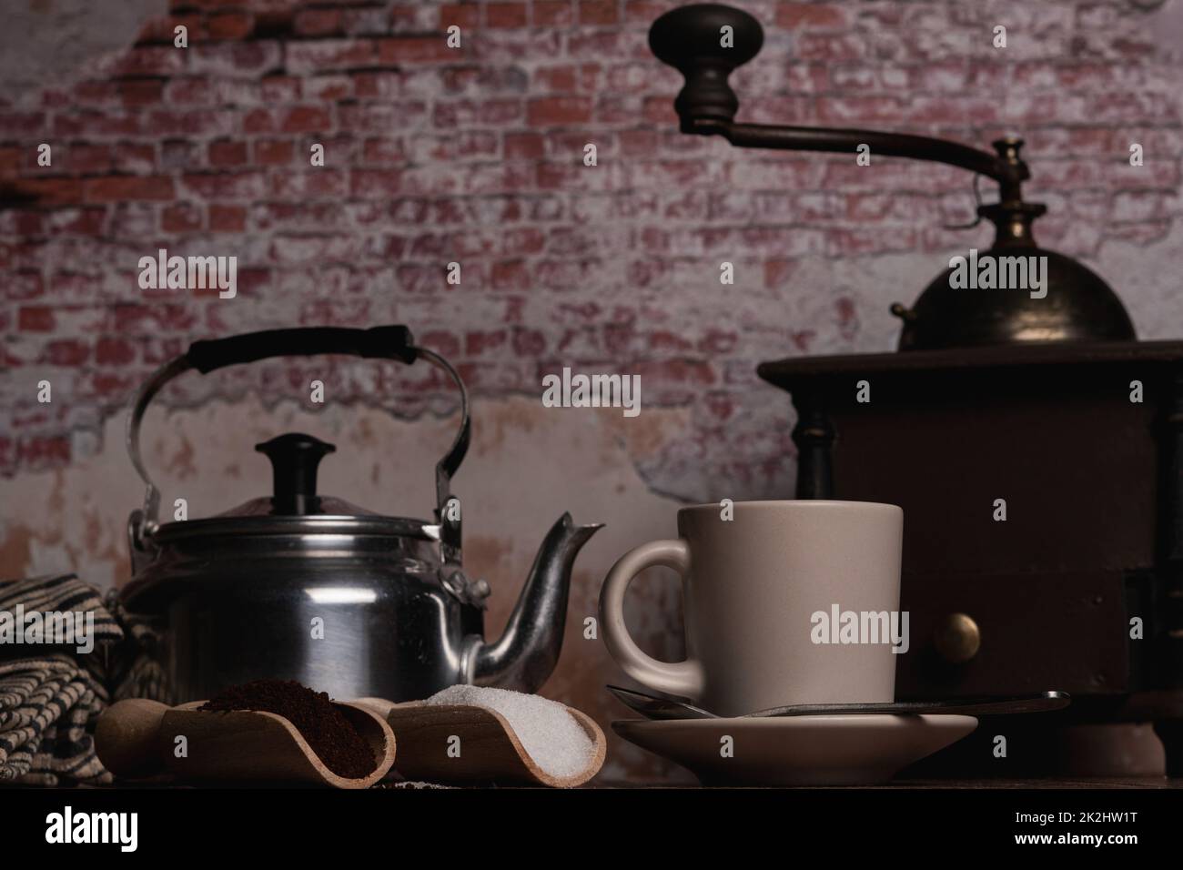 taza de café con jarra de leche, molinillo de café y cucharas de madera con café molido con azúcar Foto de stock