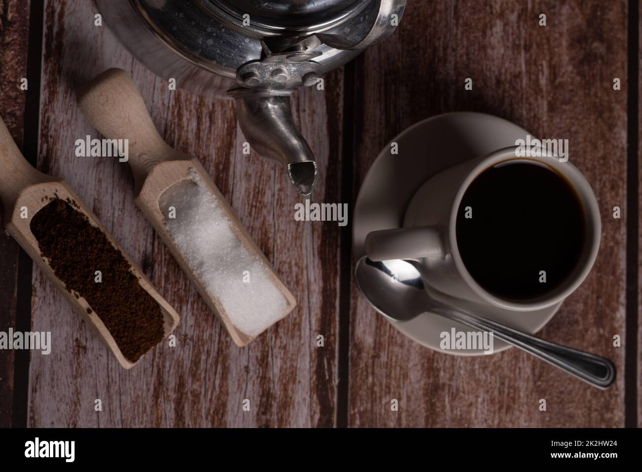 vista cenital de una taza de café con jarra de leche y cucharas de madera Foto de stock