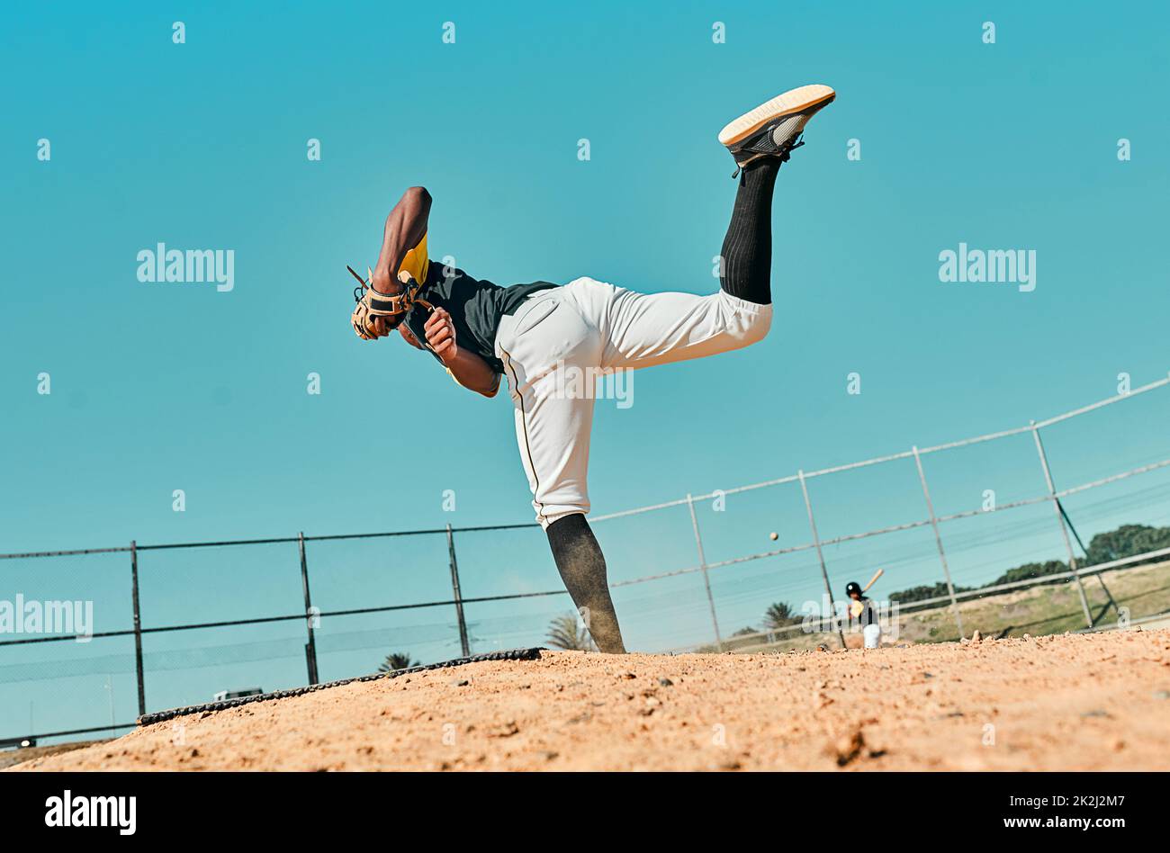 Todo lo que se necesita es todo lo que tienes. Tiro de un joven jugador de béisbol lanzando la pelota durante un juego al aire libre. Foto de stock