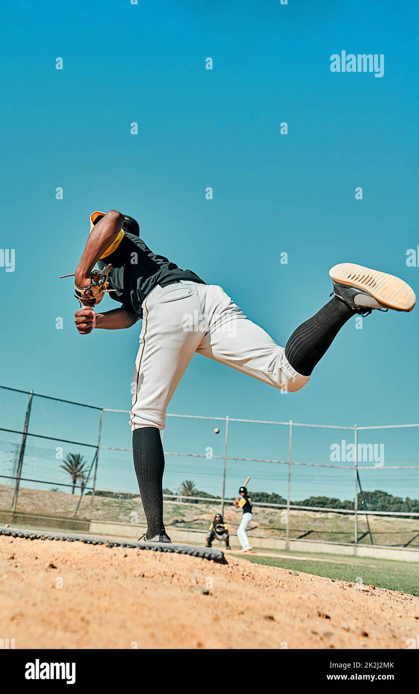 Hes dándolo todo. Tiro de un joven jugador de béisbol lanzando la pelota durante un juego al aire libre. Foto de stock