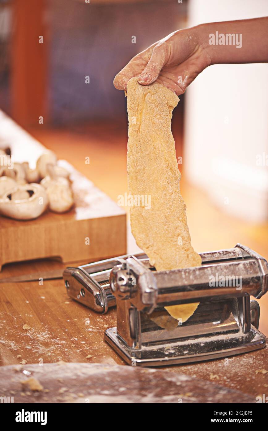 Chef rodando la masa con una máquina de pasta. máquina para hacer