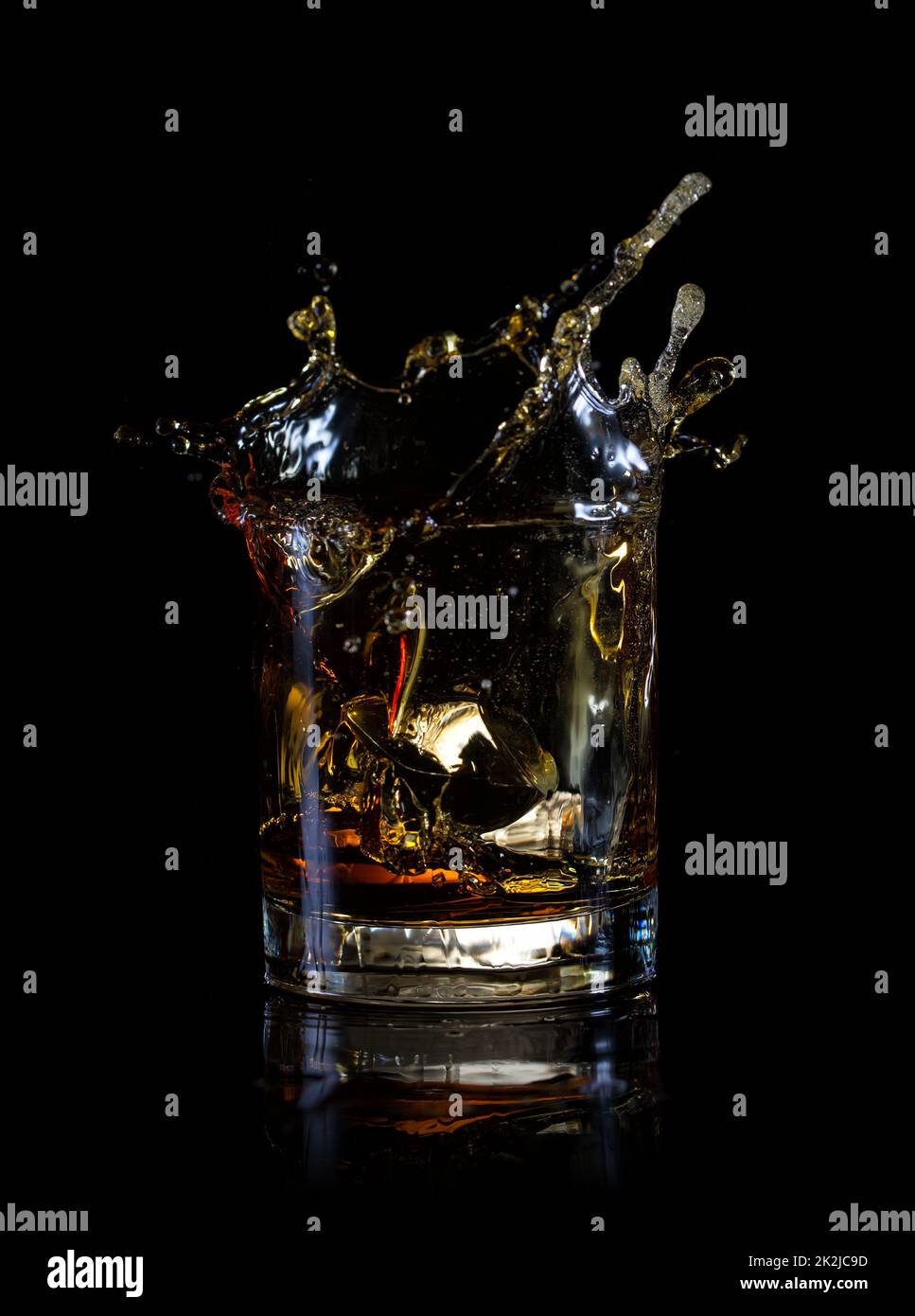 Salpicaduras de cubo de hielo en un vaso de whiskey. Foto de stock