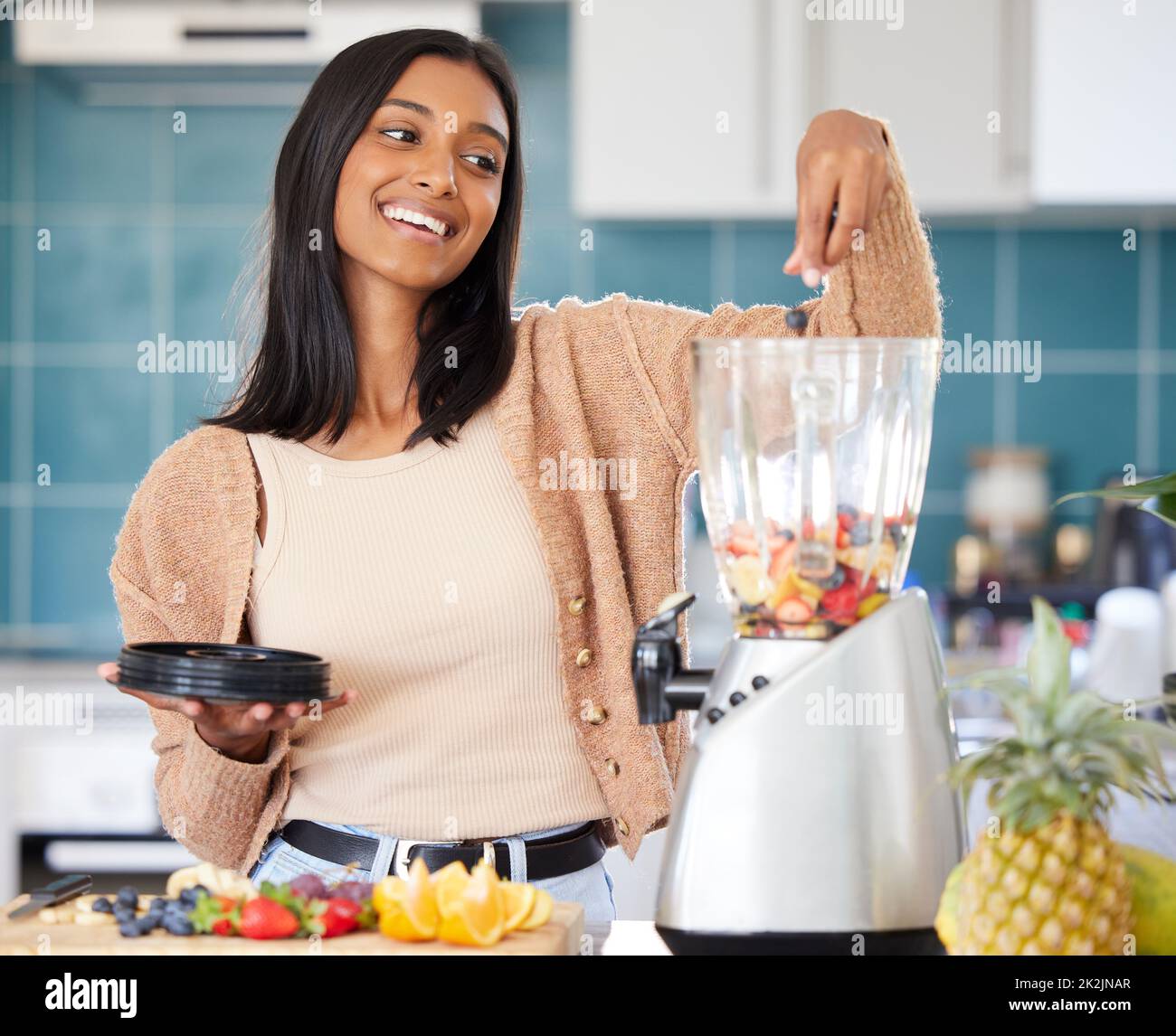 Cargando su batido con muchos ingredientes frescos. Foto de una mujer joven que prepara un batido saludable en casa. Foto de stock