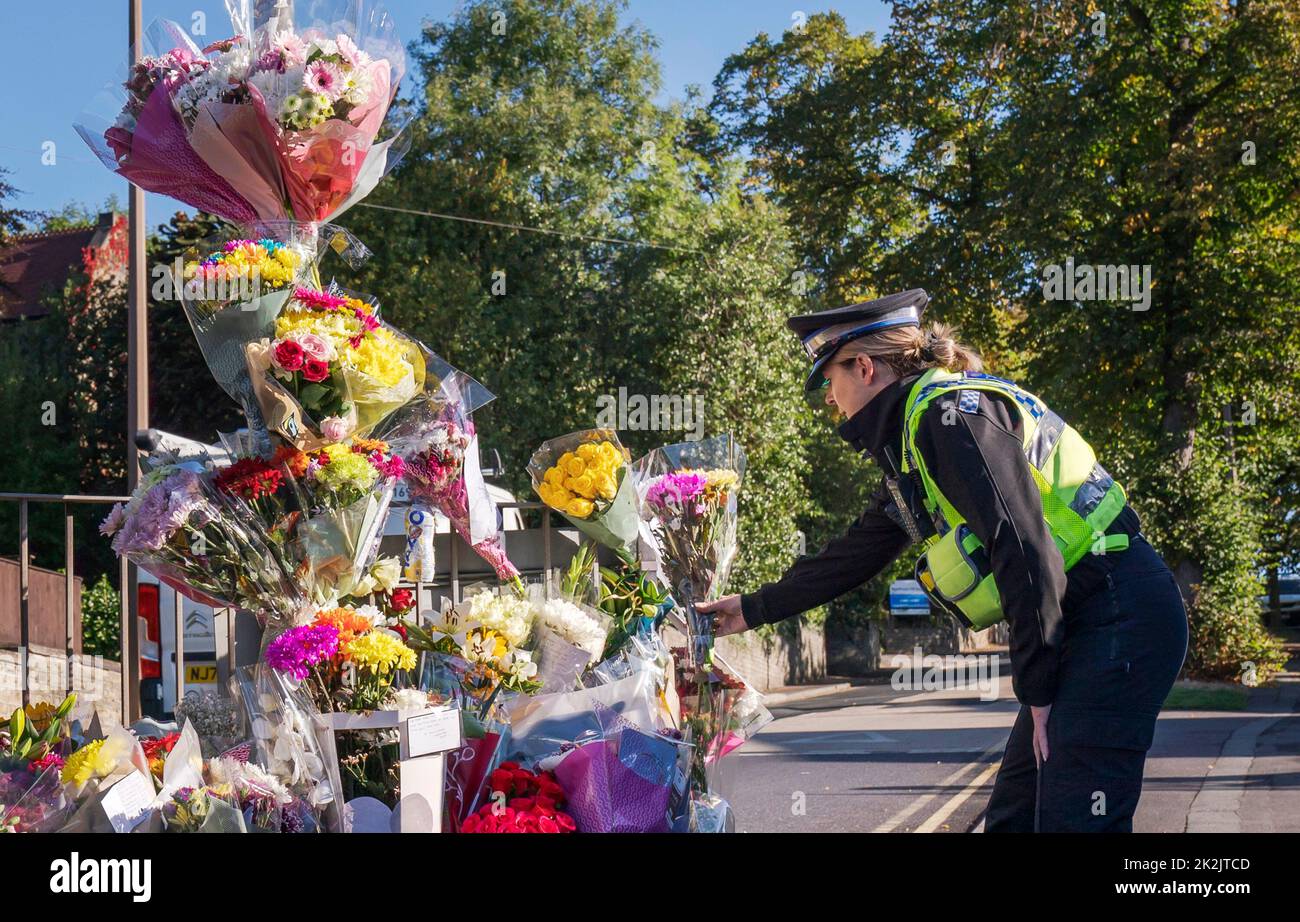 Un oficial de apoyo a la comunidad policial rinde un homenaje floral en Woodhouse Hill, Huddersfield, donde Khayri McLean, de 15 años, fue apuñalado fatalmente fuera de las puertas de su escuela. Fecha de la foto: Viernes 23 de septiembre de 2022. Foto de stock