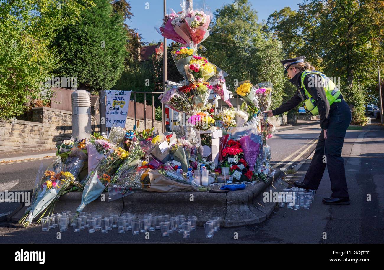 Un oficial de apoyo a la comunidad policial rinde un homenaje floral en Woodhouse Hill, Huddersfield, donde Khayri McLean, de 15 años, fue apuñalado fatalmente fuera de las puertas de su escuela. Fecha de la foto: Viernes 23 de septiembre de 2022. Foto de stock