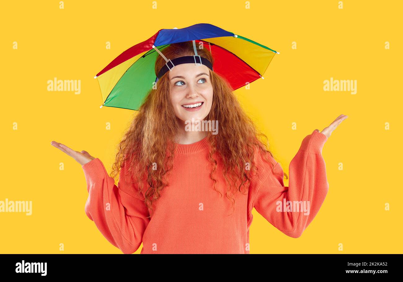 Retrato de joven feliz con sombrilla arco iris en la cabeza que protege de la lluvia o el sol. Foto de stock