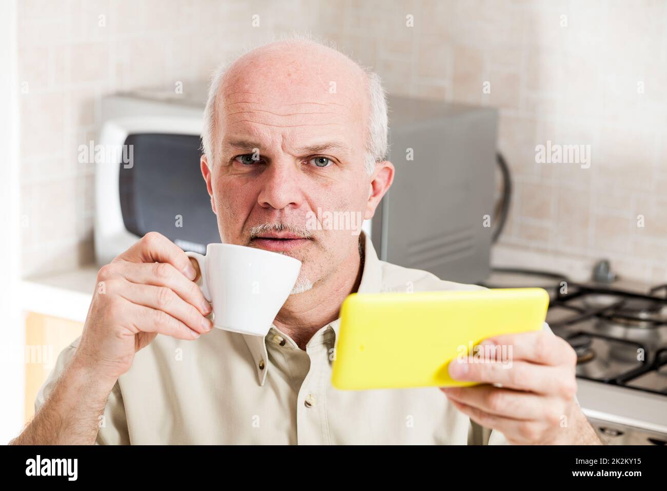 Hombre preocupado sosteniendo el vaso y el lector digital Foto de stock